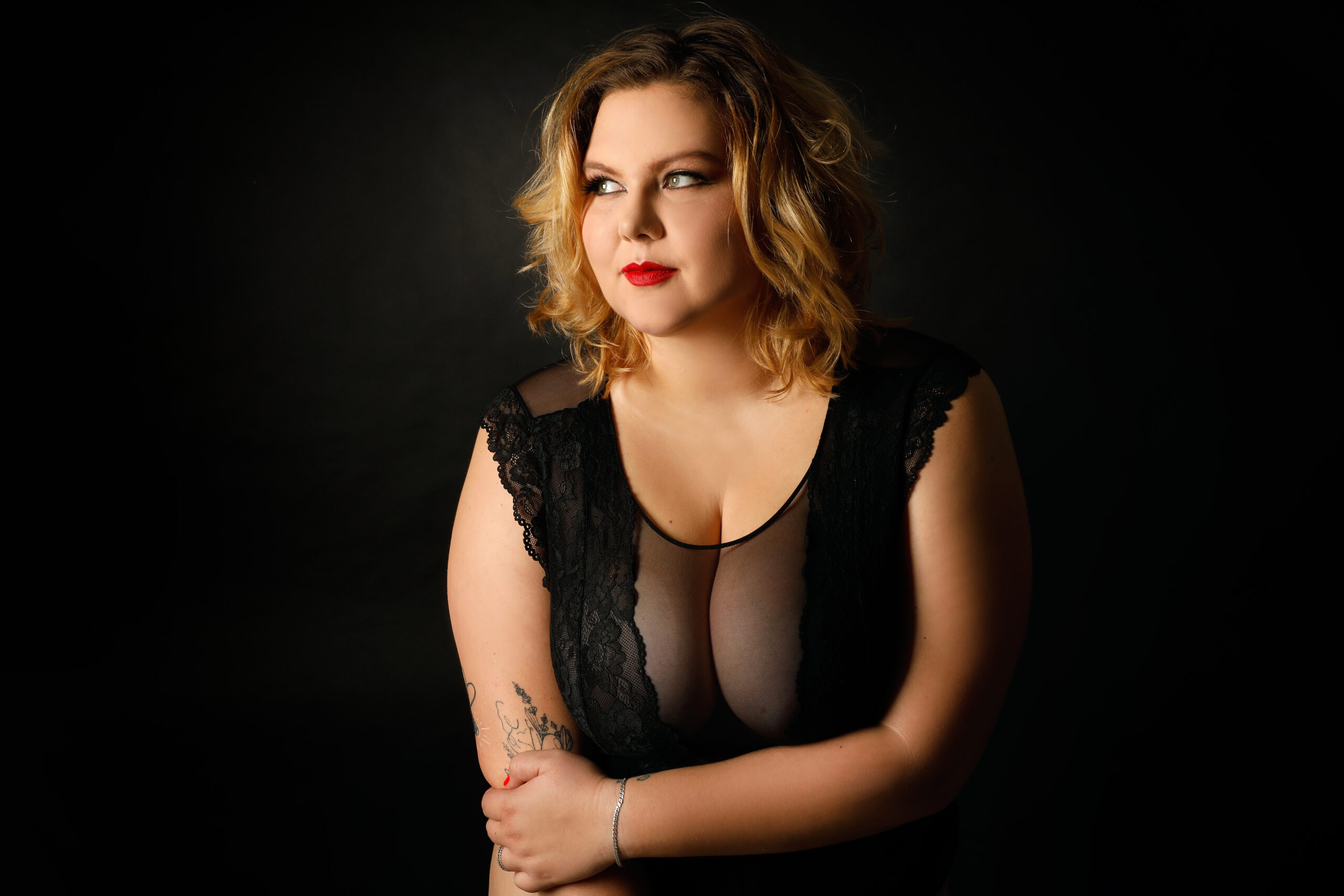 Žena na glamour focení, která je plus size modelkou a cítí se sexy v černém prádle.